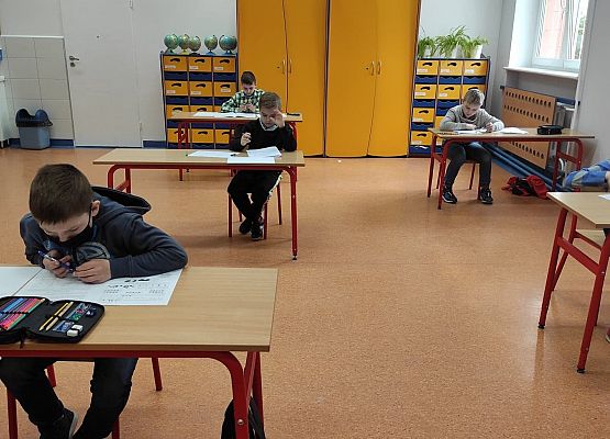 Uczniowie z młodszych klas pochyleni nad zadaniami