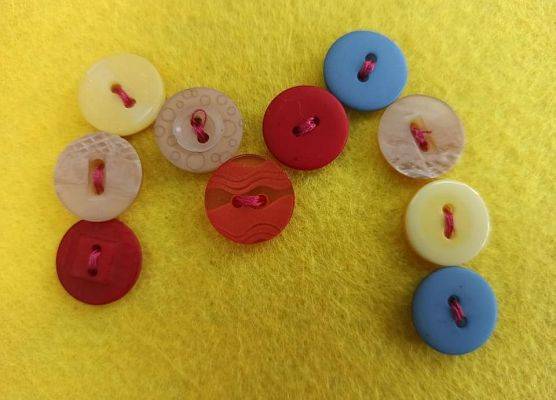 literka m z guzików na żółtym tle