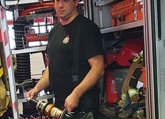 Strażak - sekc. A. Chołka, prezentuje hydrauliczne nożyce strażackie.