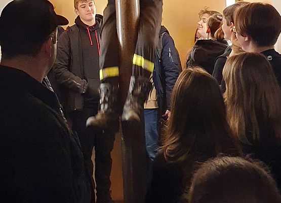 Strażak zaprezentował uczniom ześlizg po rurze.