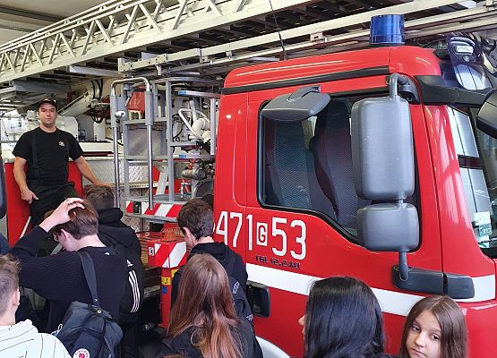 Uczniowie 8b oglądają wóz strażacki z drabiną.