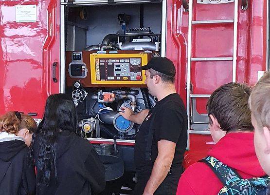 Uczniowie 8b oglądaja wyposażenie wozu strażackiego.