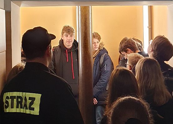 Uczniowie oglądają zainstalowane specjalne rury (ześlizgi) do szybkiego zjeżdżania do garaży