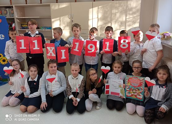 uczniowie z kotylionami w kształcie serduszek śpiewają hymn Polski