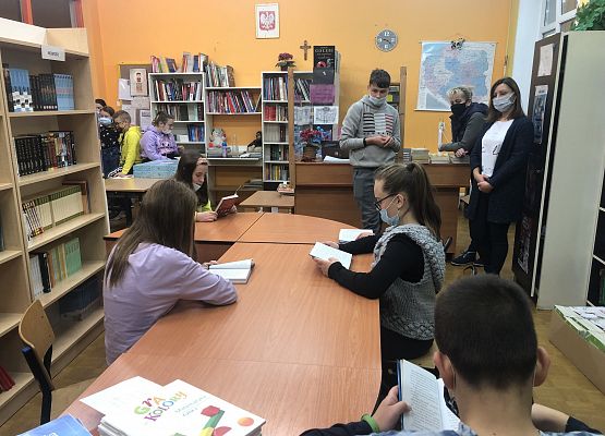 uczniowie przeglądają zasoby biblioteki