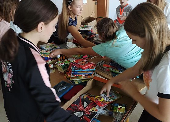 Uczniowie klasy 5b pakują zebrane przybory szkolne