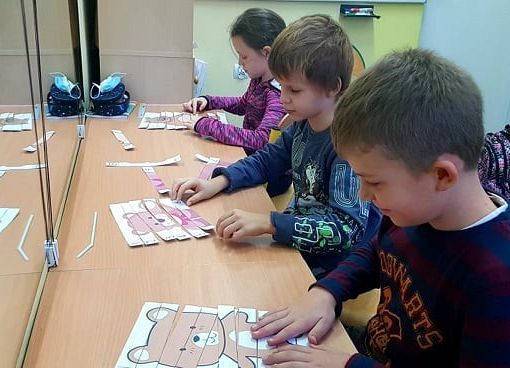 Uczniowie układają puzzle misia.