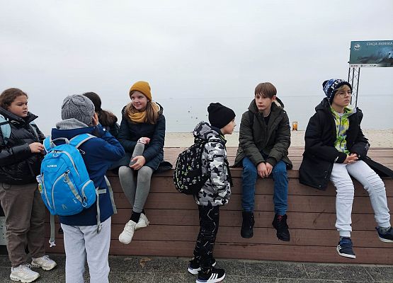 dzieci siedzą na murku na Helu