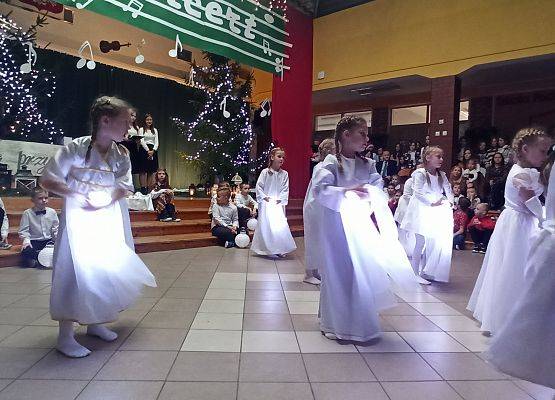 dziewczynki ubrane na biało tańczą ze świecącymi szarfami