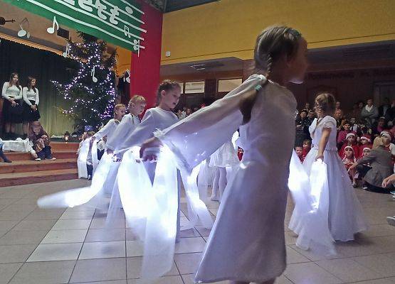 dziewczynki ubrane na biało tańczą ze świecącymi szarfami, trzymają ręce w tyle