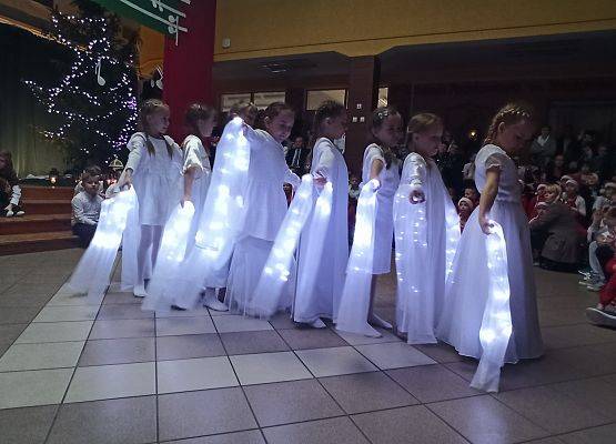 dziewczynki ubrane na biało tańczą ze świecącymi szarfami, stoją jedna za drugą