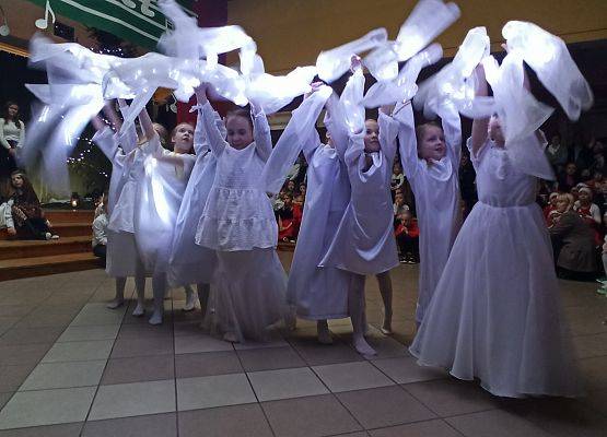 dziewczynki ubrane na biało tańczą ze świecącymi szarfami, podnoszą ręce do góry