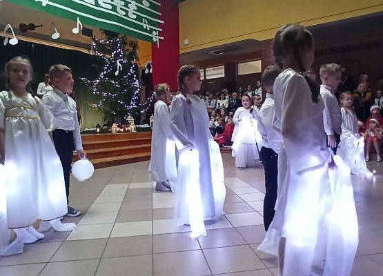 dziewczynki ubrane na biało tańczą ze świecącymi szarfami, chłopcy tańczą z lampionami