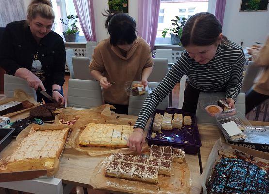 uczniowie z paniami pakują ciasto do pudełek