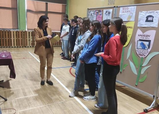 Nauczyciel rozdaje uczniom nagrody.