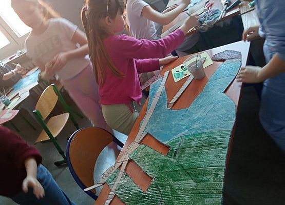 Uczniowie malują kartonowe postacie.