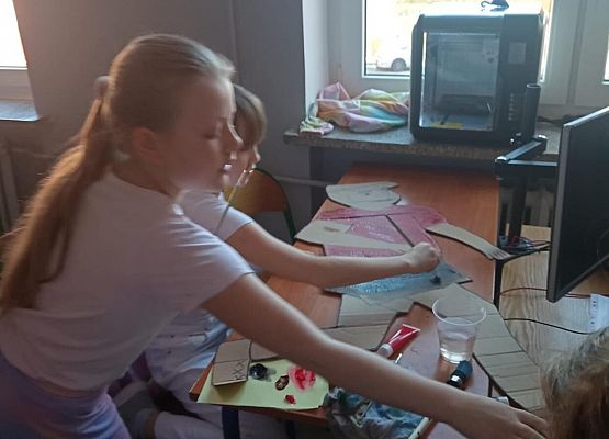 Uczniowie malują kartonowe postacie.