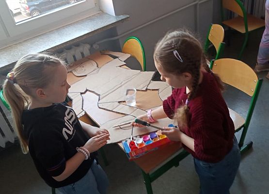 Uczniowie malują kartonowe postacie.