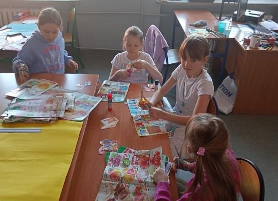 Uczennice przyklejają kartki na żółty brystol