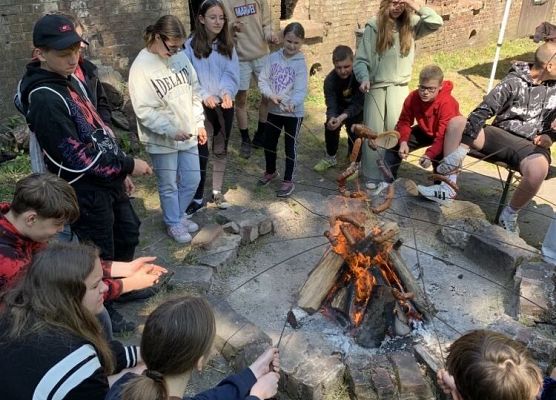Dzieci pieką kiełbaski przy ognisku