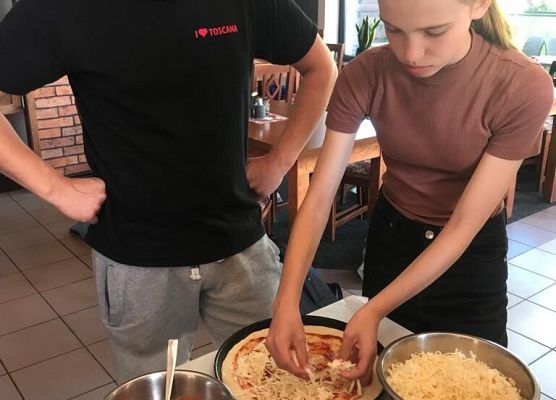 Uczennica nakłada na pizzę składniki.