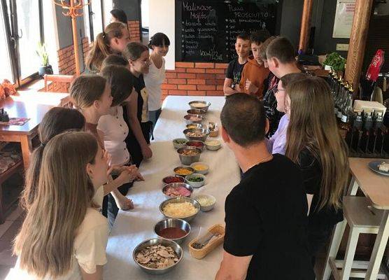 Uczniowie stoją wokół stołu z jedzeniem.