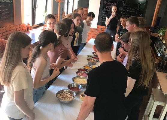 Uczniowie stoją wokół stołu z jedzeniem.