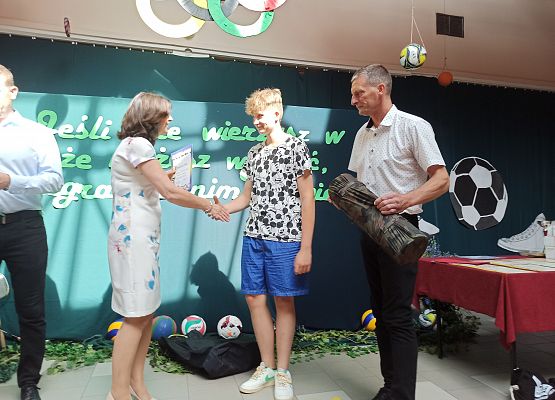 Pani Dyrektor i Pan Adam wręczają Sewerynowi nagrodę za wyniki sportowe