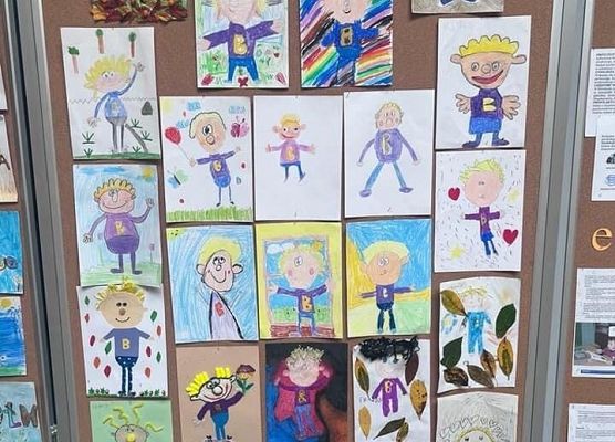 Tablica na ktorej wiszą kolorowe prace plastyczne