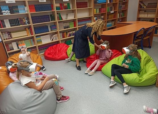 Na dużych kolorowych pufach siedzą uczniowie w googlach.