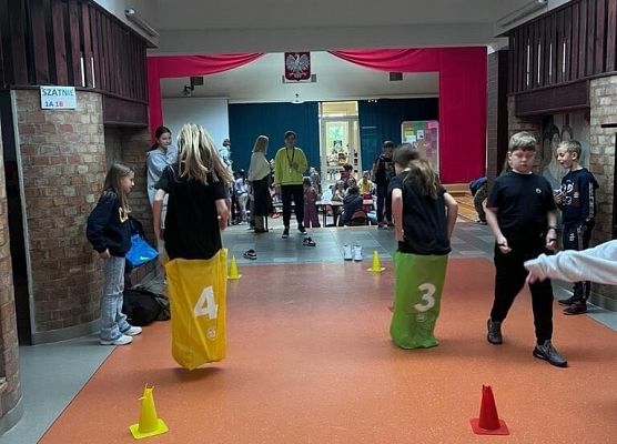 Dwójka uczniów skacze w kolorowych workach