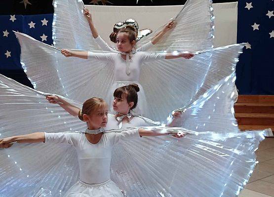 taniec dziewczynek z klas 1-3 ze świecącymi skrzydłami