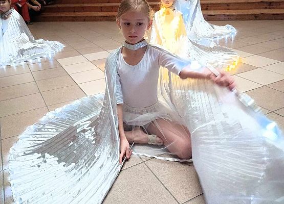 taniec dziewczynek z klas 1-3 ze świecącymi skrzydłami