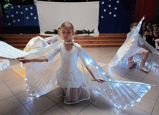 taniec dziewczynek z klas 1-3 ze świecącymi skrzydłami