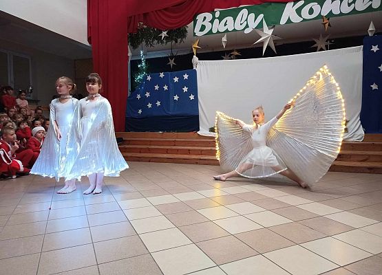 taniec dziewczynek z klas 1-3 ze świecącymi skrzydłami