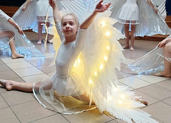 taniec dziewczynek z klas 1-3 ze świecącymi skrzydłami