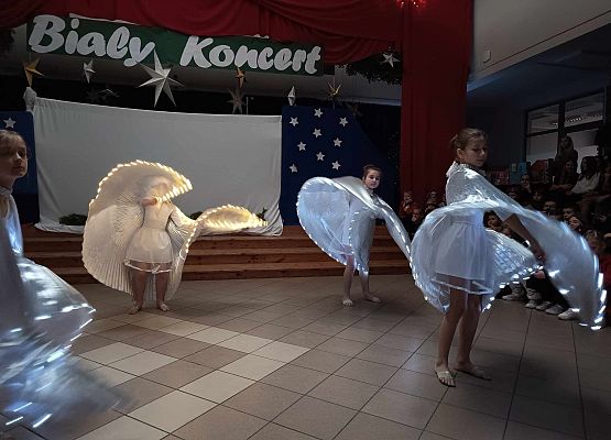 taniec dziewczynek z klas 1-3 ze świecącymi skrzydłami
