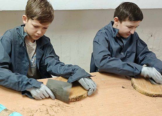 chłopcy szlifują deseczki