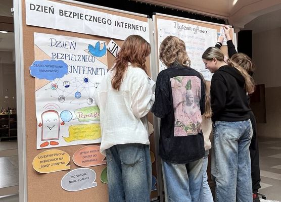 Uczennice przyczepiają do tablicy korkowej informacje