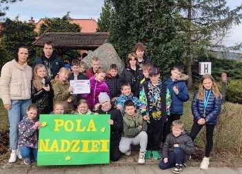 Uczniowie trzymają w ręce zielony plakat , pozują w grupie do zdjęcia