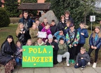 Uczniowie trzymają w ręce zielony plakat , pozują w grupie do zdjęcia.