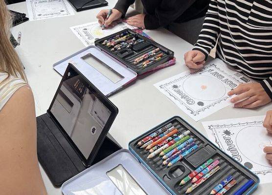 Na stoliku leży tablet, kredki i kolorowanka