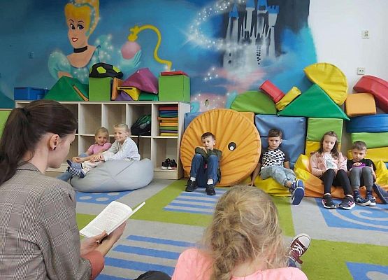 Uczniowie w trakcie zajęć w świetlicy szkolnej słuchają baśni Hansa Christiana Andersena.