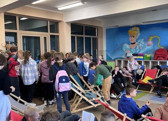 Uczniowie siedzą na leżakach.