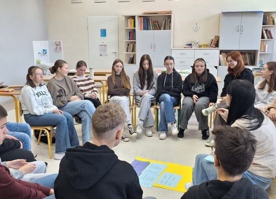 Uczniowie siedzą na krzesłach w kole