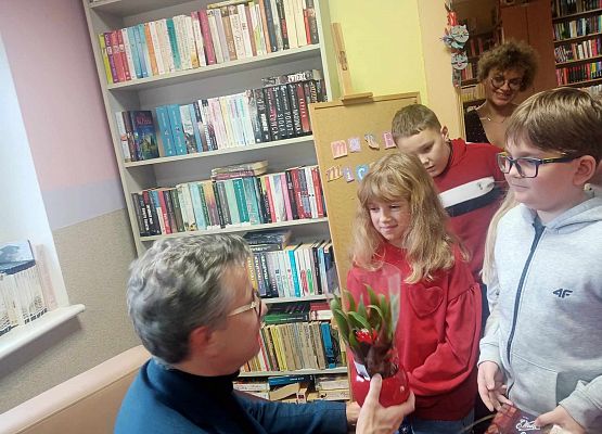 dzieci wręczają pisarzowi kwiatek i dziękują za udział w spotkaniu