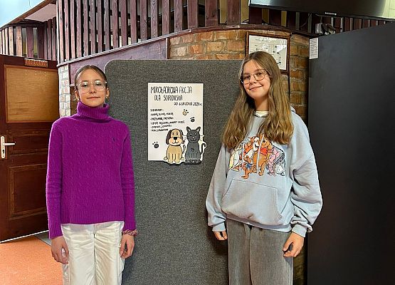 dziewczynki stoją przy plakacie