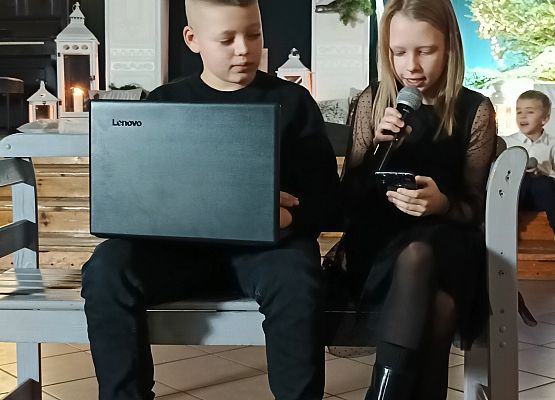 chłopiec z laptopem i dziewczynka siedzą na ławce