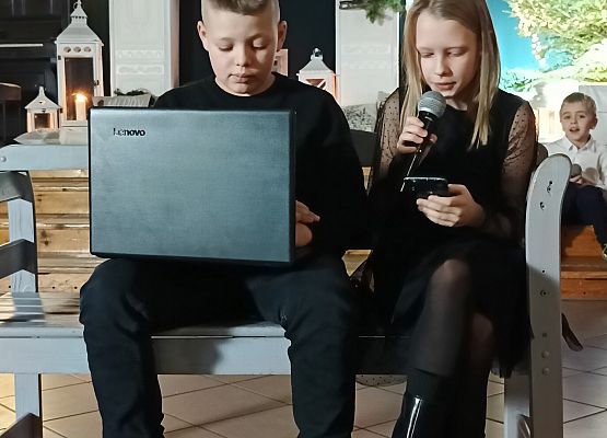 chłopiec z laptopem i dziewczynka siedzą na ławce