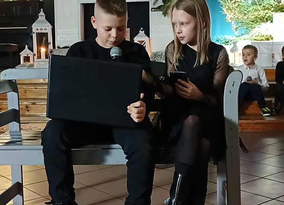 chłopiec z laptopem i dziewczynka siedzą na ławce